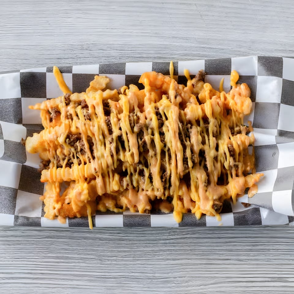 Slaw Burger's waffle fries topped with melted cheese and ground beef, served in a checkered paper tray.