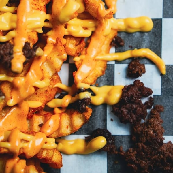 Close-up of Slaw Burger's waffle fries topped with melted cheese and ground beef.