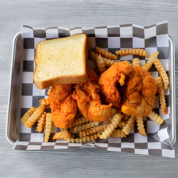 Crispy fried chicken tenders, crinkle-cut fries, and a slice of white bread on a checkered paper-lined tray.
