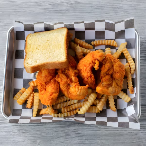 Crispy fried chicken tenders, crinkle-cut fries, and a slice of white bread on a checkered paper-lined tray.