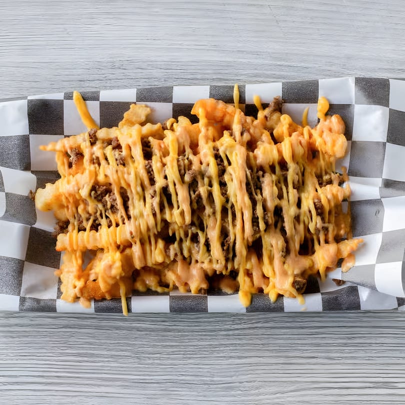 Slaw Burger's waffle fries topped with melted cheese and ground beef, served in a checkered paper tray.